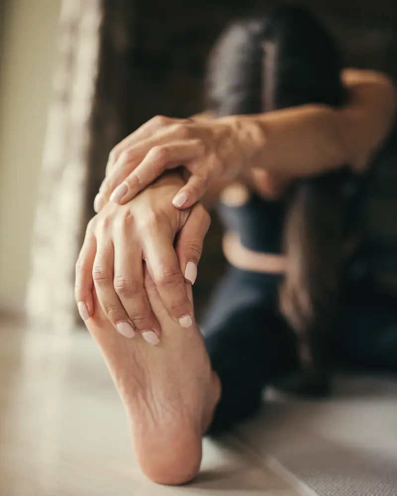 Hands holding a stretched foot during a mobility exercise